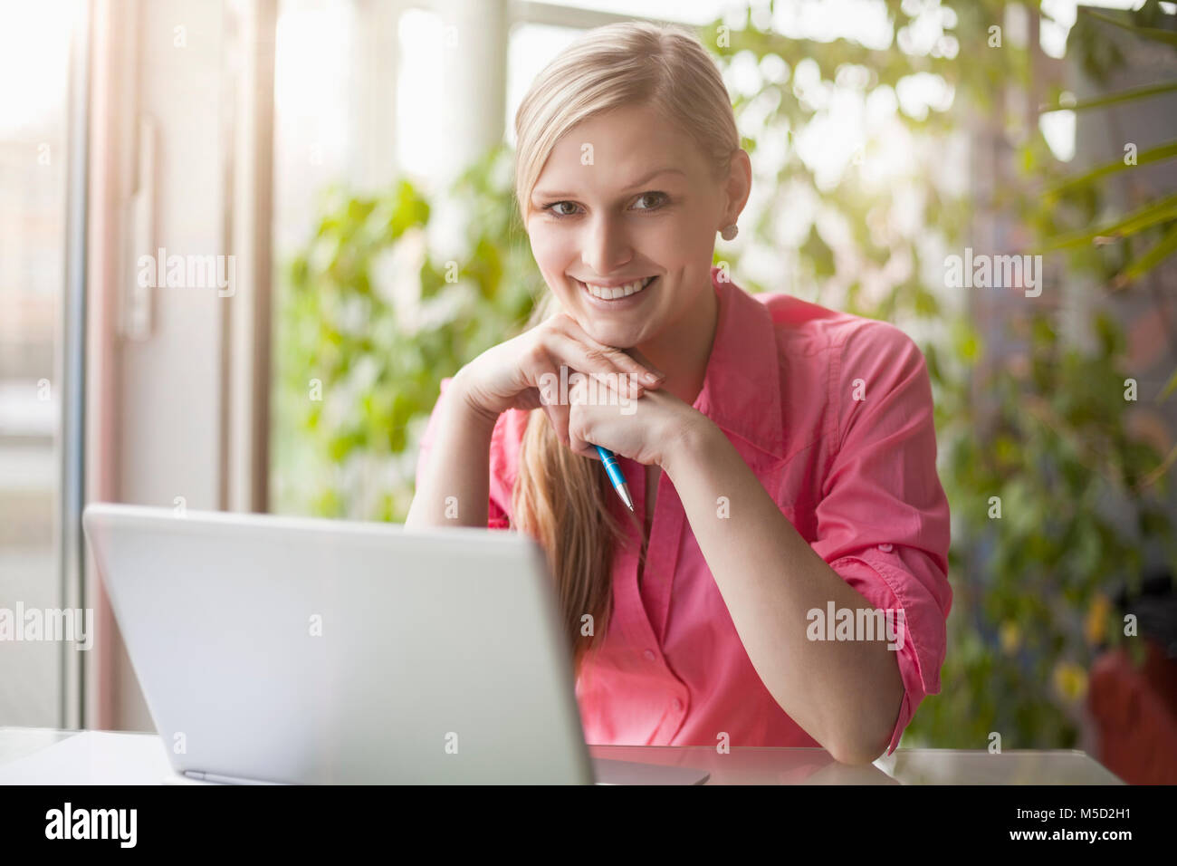 Porträt der lächelnde junge Geschäftsfrau mit Laptop am Schreibtisch im Büro Stockfoto