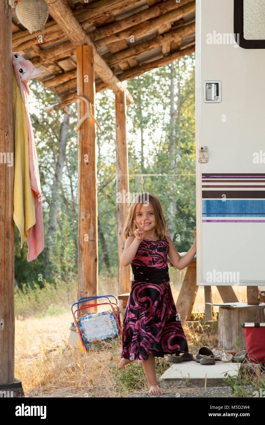 Porträt Lächeln, selbstbewusste Mädchen im Kleid Gestik Frieden Zeichen außerhalb des ländlichen Camper Stockfoto