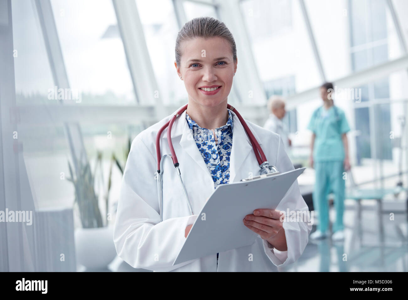 Porträt Lächeln, selbstbewusste Frau Doktor mit Zwischenablage im Krankenhaus Stockfoto