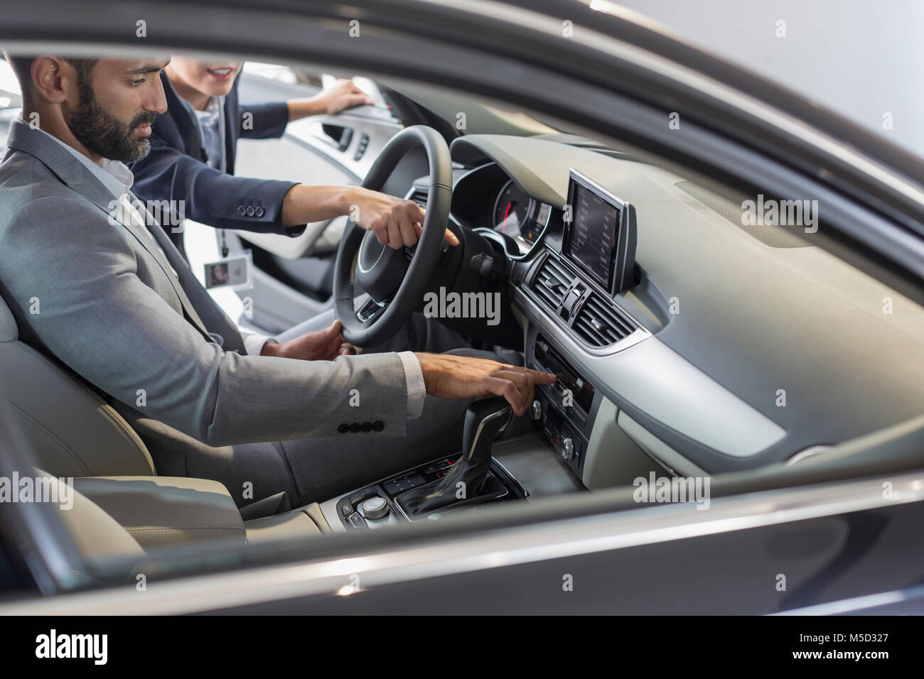 Auto Verkäuferin zeigen, erklären, neues Auto zu männlichen Kunden im Fahrersitz Stockfoto