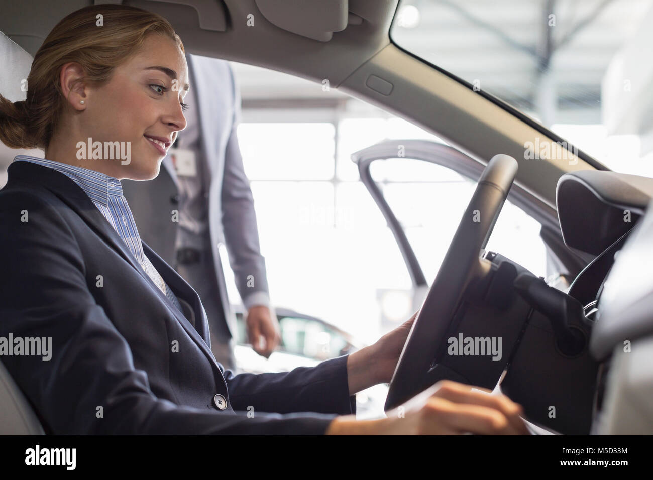 Lächelnde Frau surfen neues Auto, sitzen im Fahrersitz im Auto Dealership Stockfoto