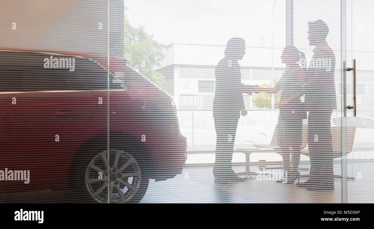 Autoverkäufer Händeschütteln mit ein paar Kunden in Auto Dealership showroom Stockfoto