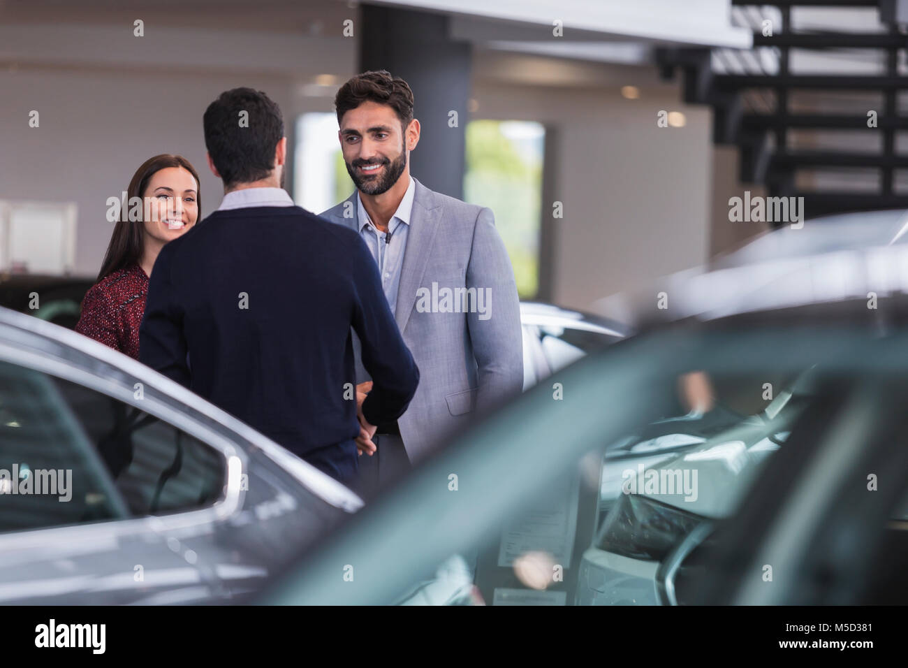 Autoverkäufer Gruß, Hände schütteln mit ein paar Kunden in Auto Dealership showroom Stockfoto