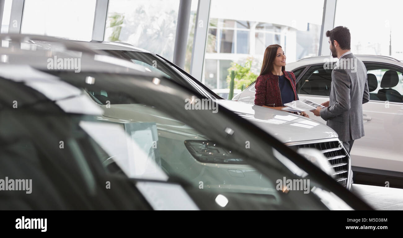 Autoverkäufer mit Broschüre im Gespräch mit weiblichen Kunden im Auto Dealership showroom Stockfoto