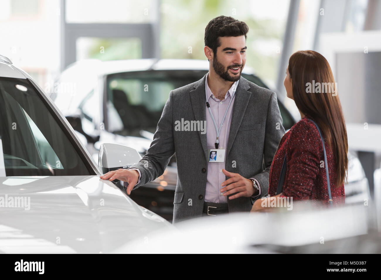 Autoverkäufer zeigt neue Auto zu weiblichen Kunden im Auto Dealership showroom Stockfoto