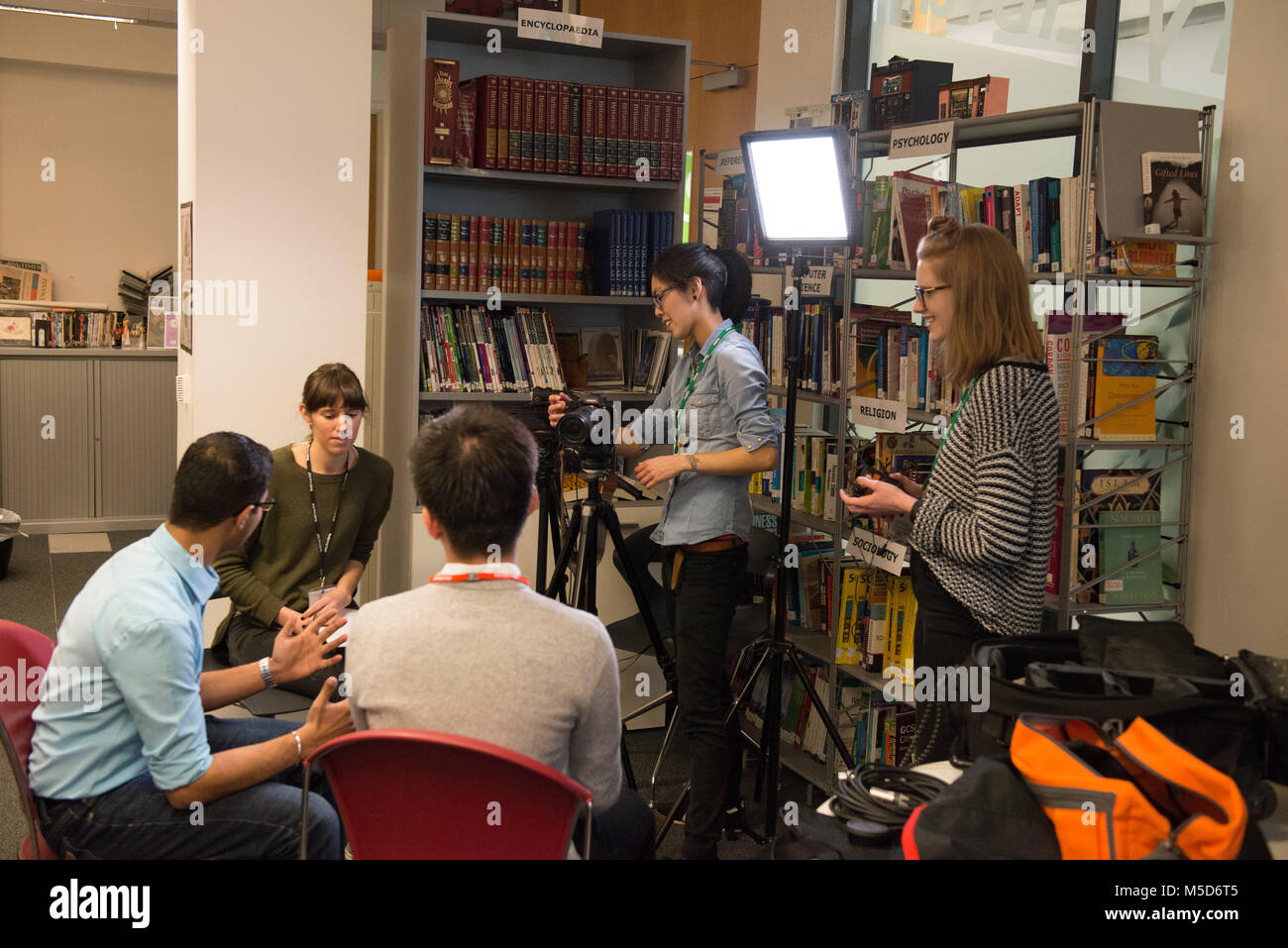 Studenten am College Campus nehmen Sie teil an einer organisierten gesellschaftlichen Ereignis in der Bibliothek und sind für eine Online Video gefilmt und interviewt Stockfoto