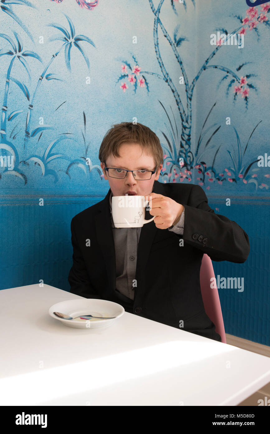 Eine junge glücklich und zuversichtlich, dass Menschen mit Down-Syndrom an einem Tisch in einem Cafe sitzt Stockfoto