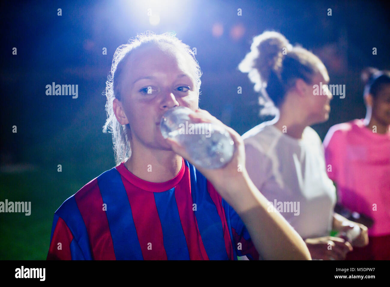 Junge weibliche Fußball-Spieler Trinken aus der Flasche Wasser Stockfoto