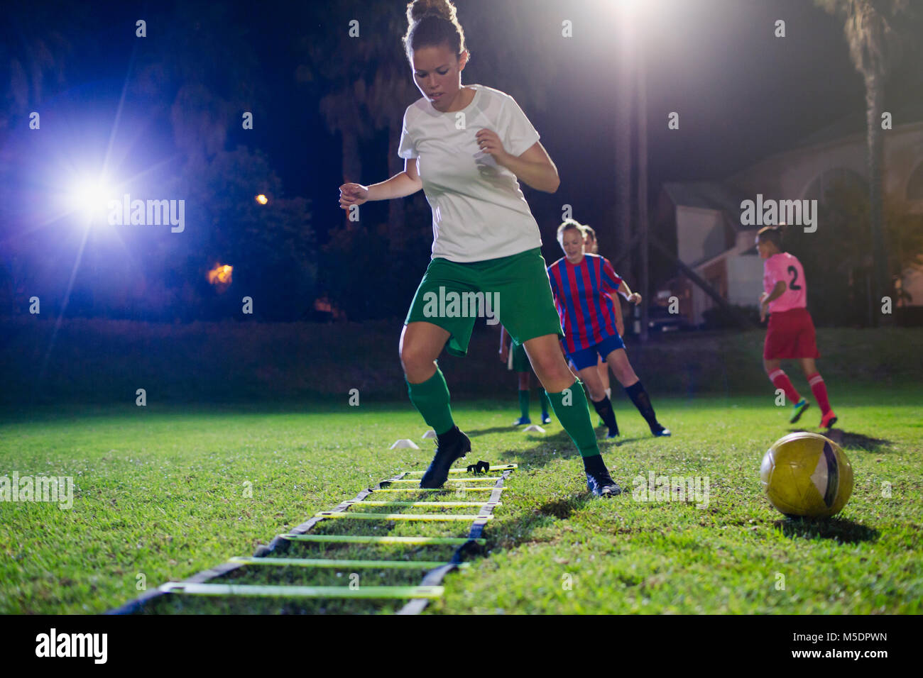Junge weibliche Fußball-Spieler üben agility Sport Sämaschine auf das Feld in der Nacht Stockfoto