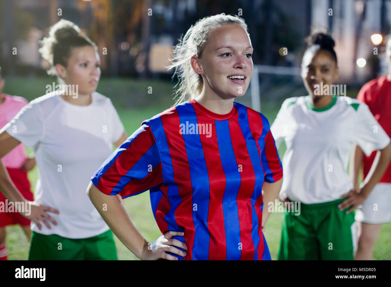 Selbstbewussten jungen weiblichen Fußball-Spieler auf den Hüften ruht auf dem Feld in der Nacht Stockfoto