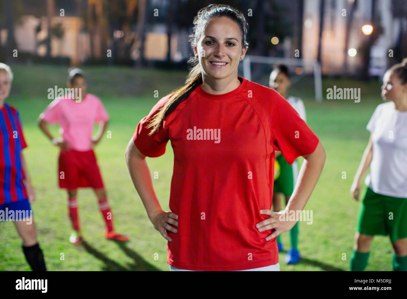 Portrait zuversichtlich, lächelnde junge weibliche Fußball-Spieler auf dem Feld in der Nacht Stockfoto