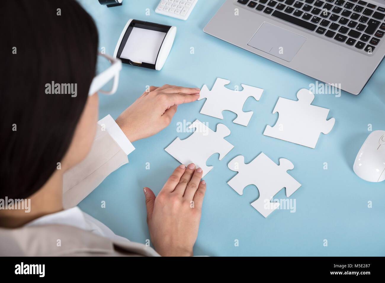 Geschäftsfrau, die versuchen, das Puzzle Stücke auf Blau Schreibtisch zu verbinden Stockfoto