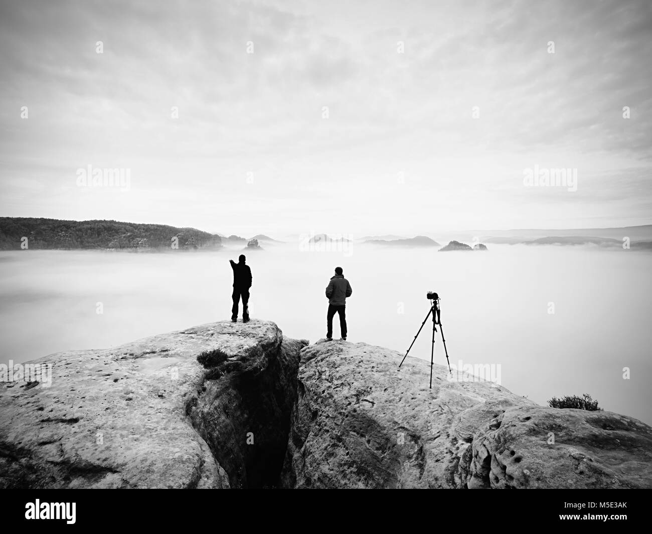Zwei warmen Mantel Fotografen mit Stativ fotografieren der herbstlichen Landschaft unter Berg. Regnerische nebligen Tag in den Bergen mit bewölkter Himmel, kalt in Stockfoto