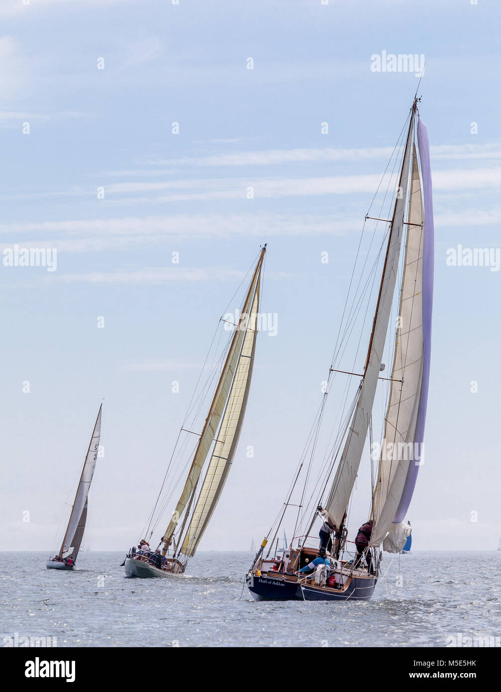 Drei klassische Holzboote segeln in den Abstand unter vollen Segeln. Stockfoto