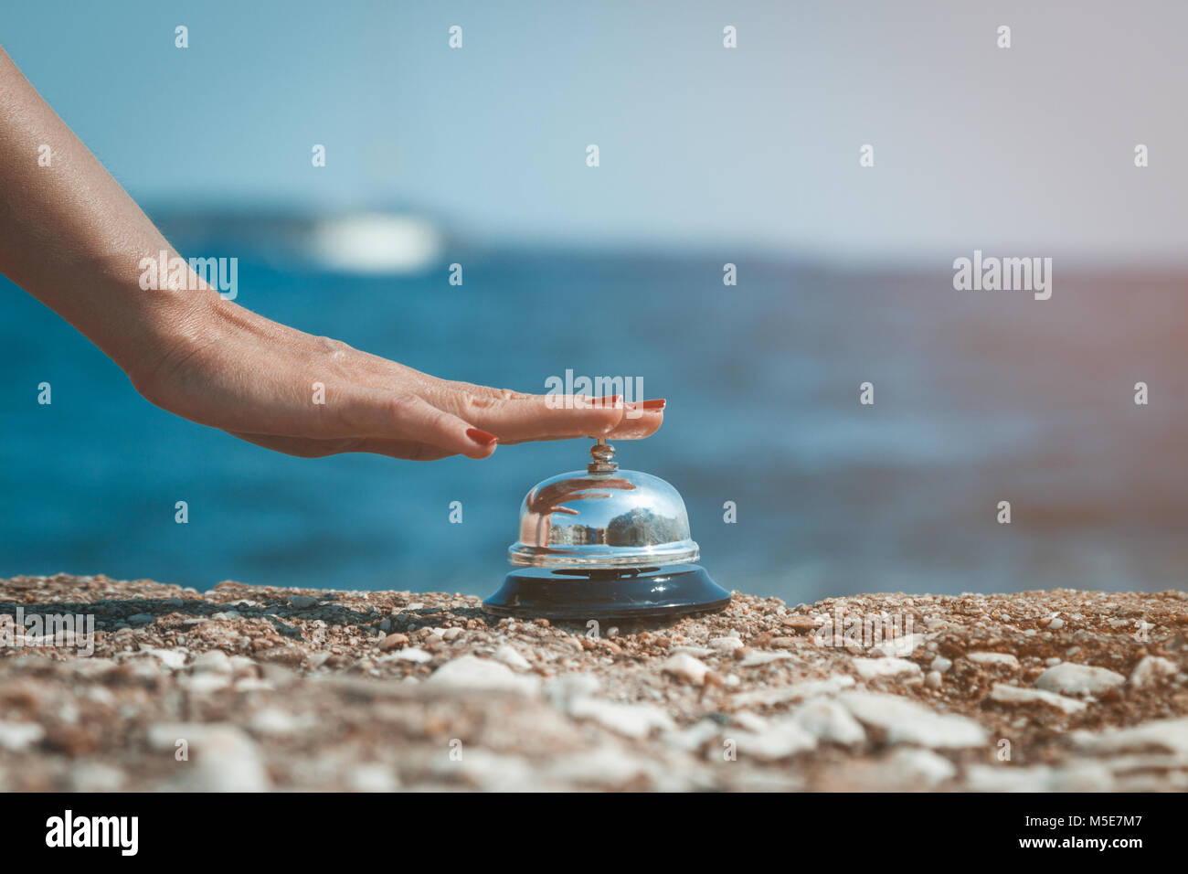 Weibliche drücken läutenden Glocke am Meer. Sommer Urlaub und Reisen Konzepte. Stockfoto
