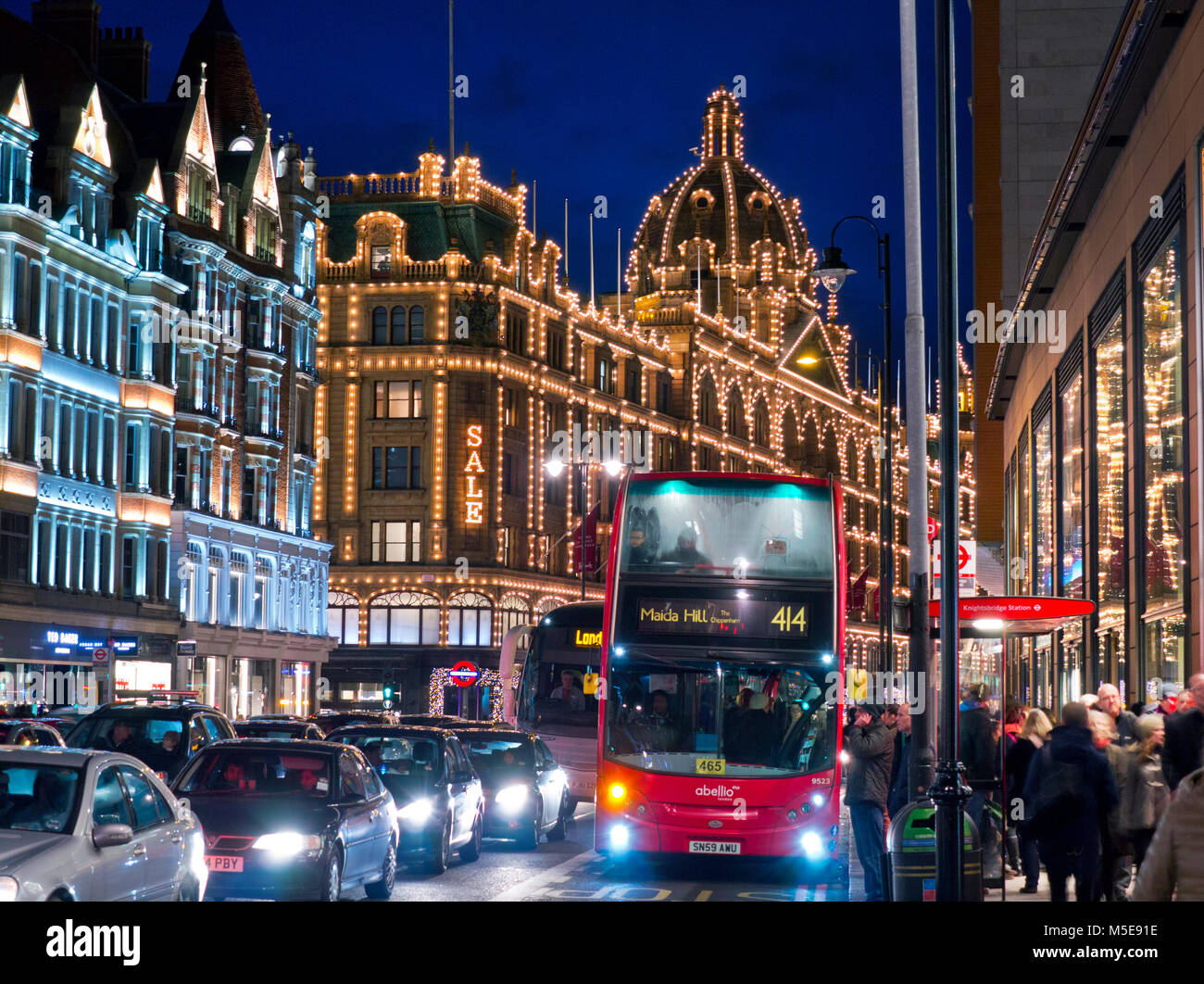 KNIGHTSBRIDGE WINTERVERKAUF Harrods Kaufhaus in der Nacht beleuchtet 'Verkauf' Schild Käufer rot Bus Blur Verkehr Brompton Road Knightsbridge London SW1 Stockfoto