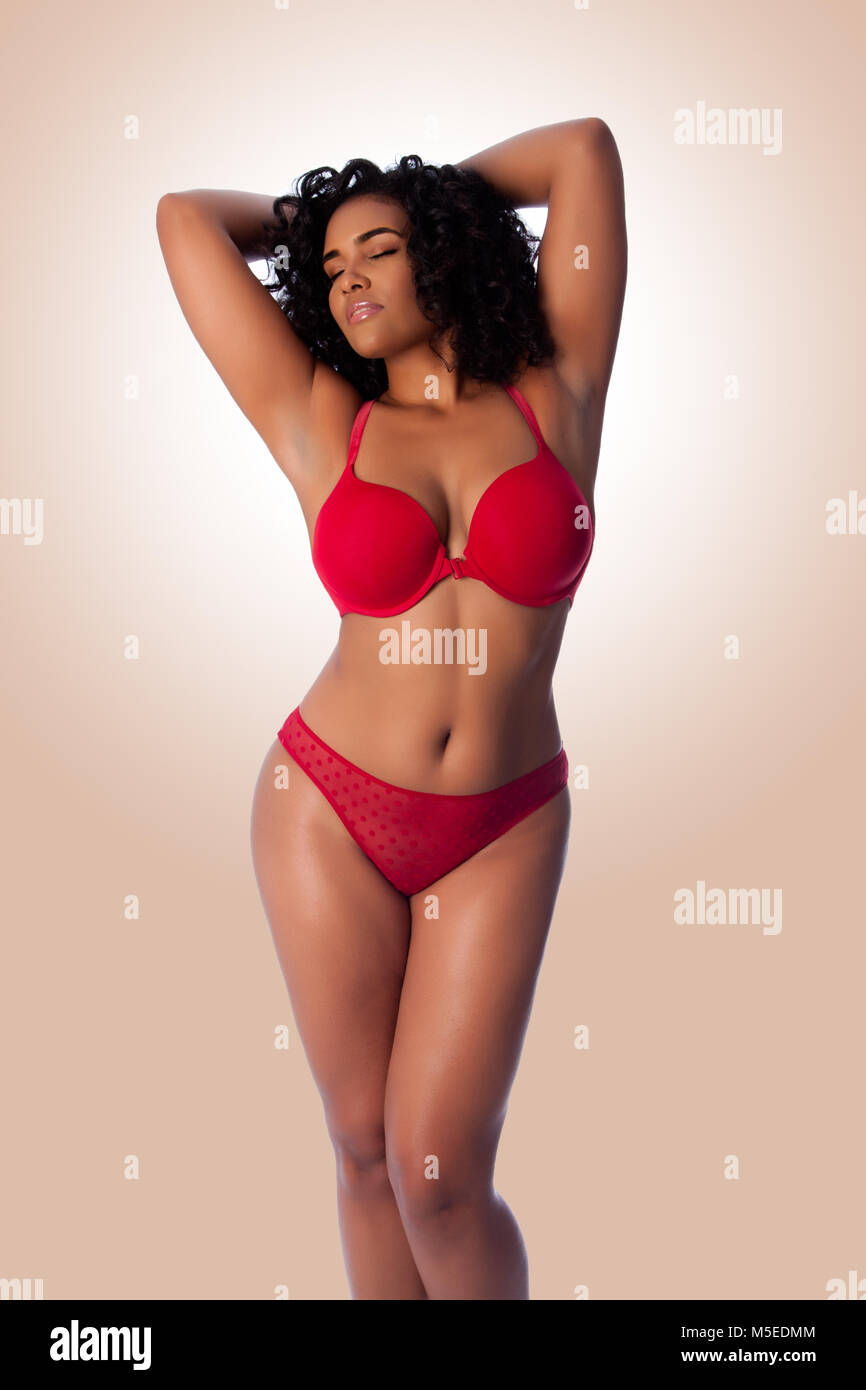 Schöne happy Plus size sexy Frau mit lockigem Haar in roten dessous BH und  Tanga Unterwäsche Stockfotografie - Alamy