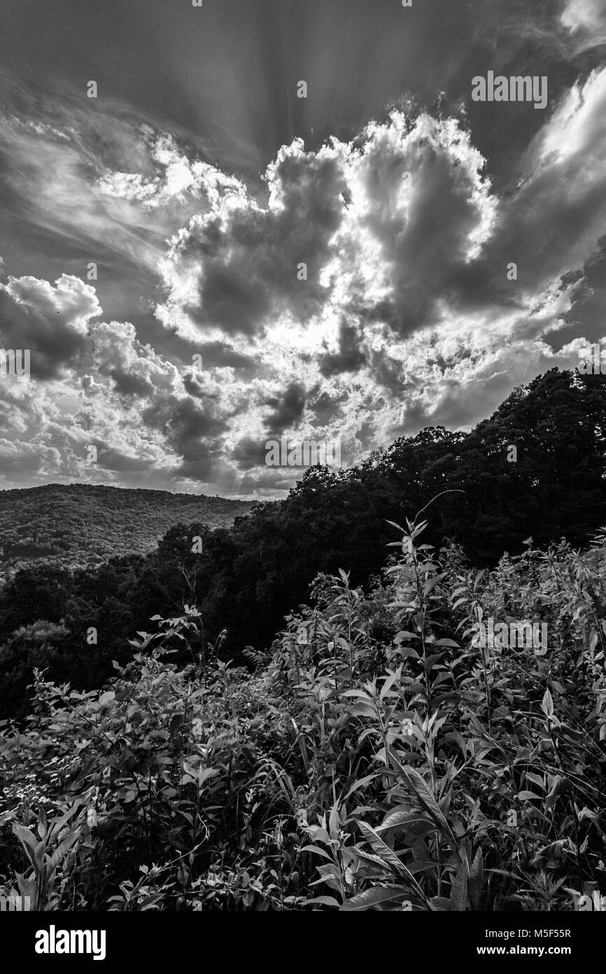 Dramatische Wolken und Sonnenstrahlen, bewegen Sie den Mauszeiger über einen Hügel und Laub auf dem Blue Ridge Parkway in Asheville, NC, USA Stockfoto