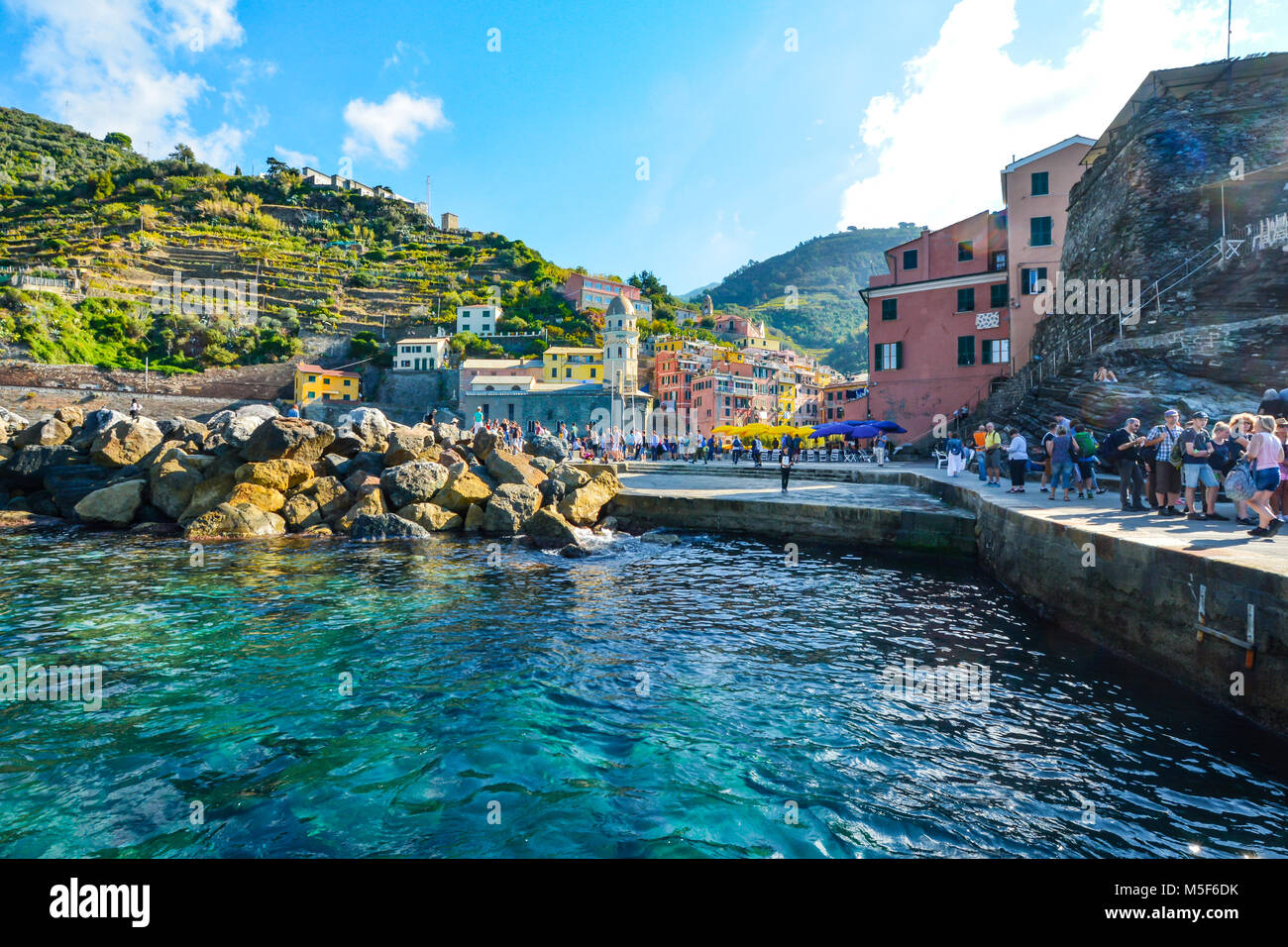 Touristen genießen das Meer und die Stadt an einem sonnigen Sommermorgen am Hang Dorf Vernazza Italien, Teil der Cinque Terre an der italienischen Riviera Stockfoto