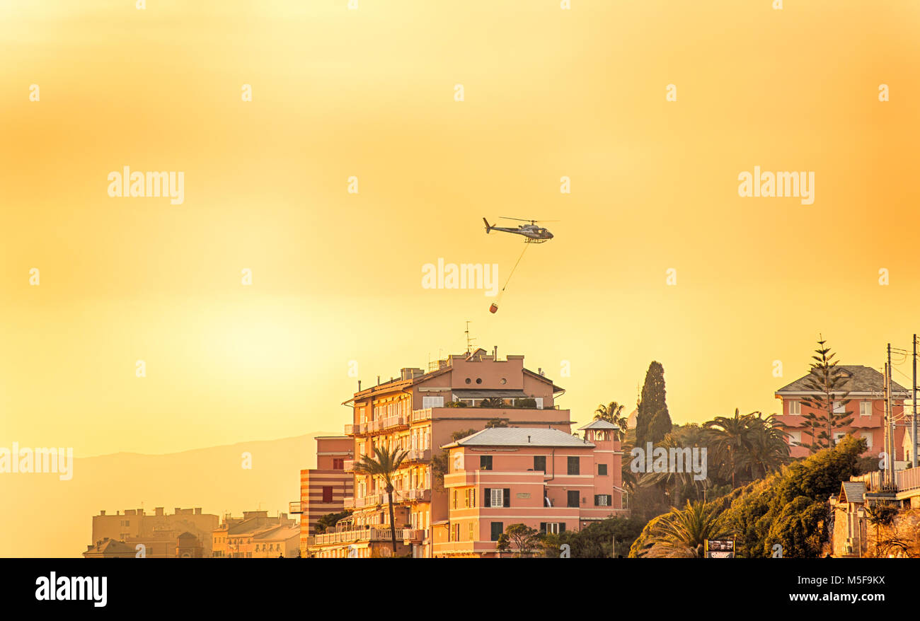 Helikopter fliegt über die Häuser bei einem Brand bei Sonnenuntergang Stockfoto