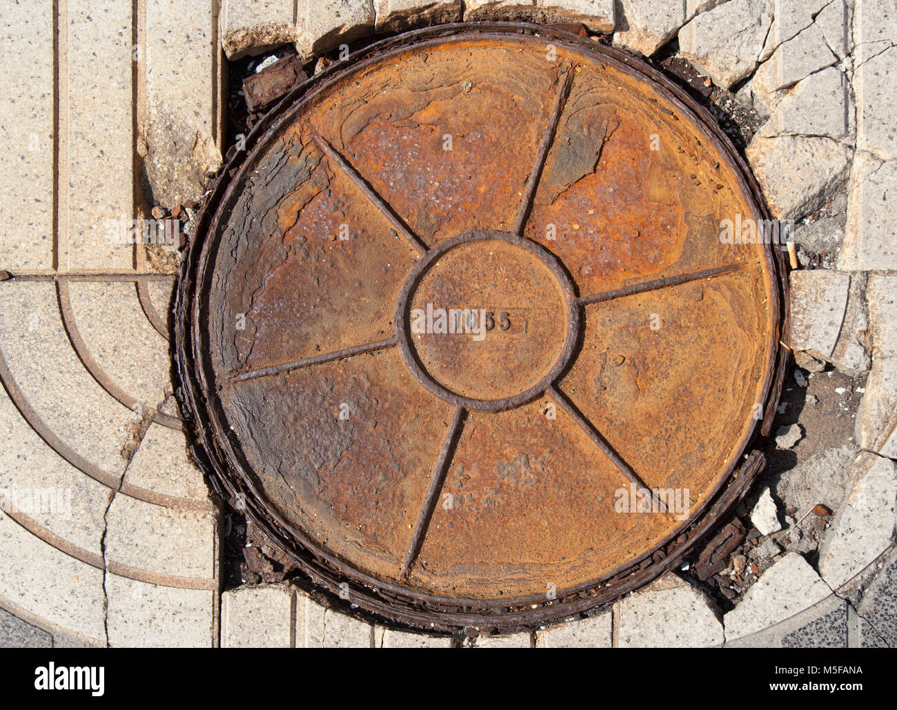 Runde rusty Kanaldeckel Nummer 1055, Sonnig Stockfoto