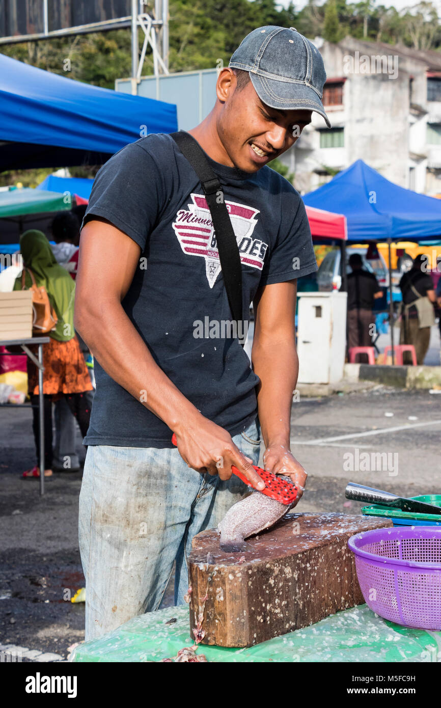 Cameron Highlands, Malaysia, 17. Dezember 2017: Verkäufer schabt die Schuppen der Fische mit einem Messer Stockfoto