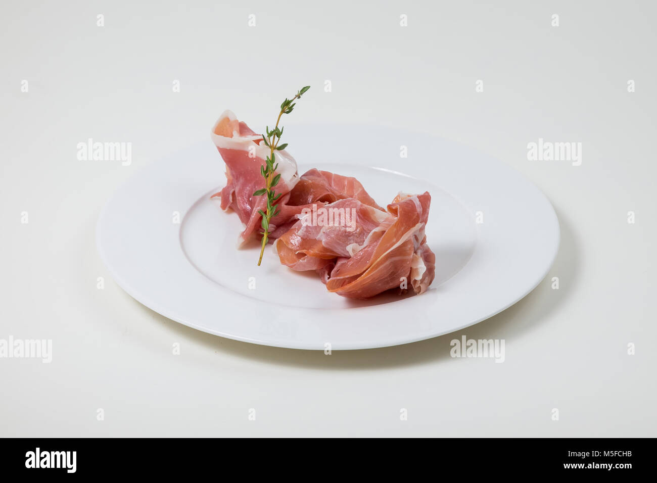 Parma Schinken auf einem weißen Teller auf weißem Hintergrund Stockfoto