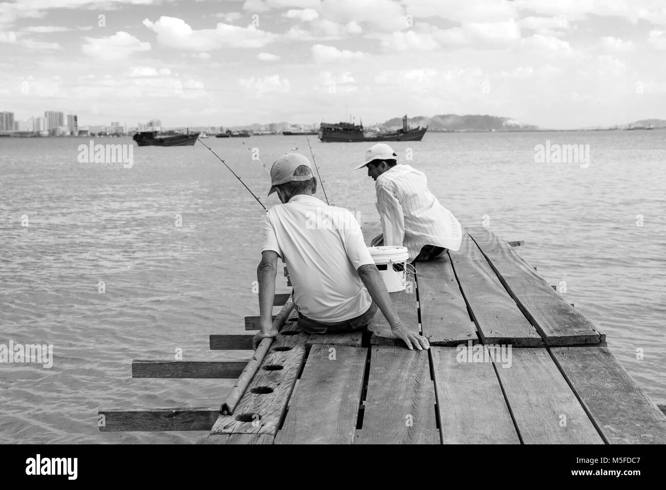 Penang, Malaysia, 19. Dezember 2017: Zwei Fischer für den Fang des Tages auf dem Holzsteg in Georgetown warten Stockfoto