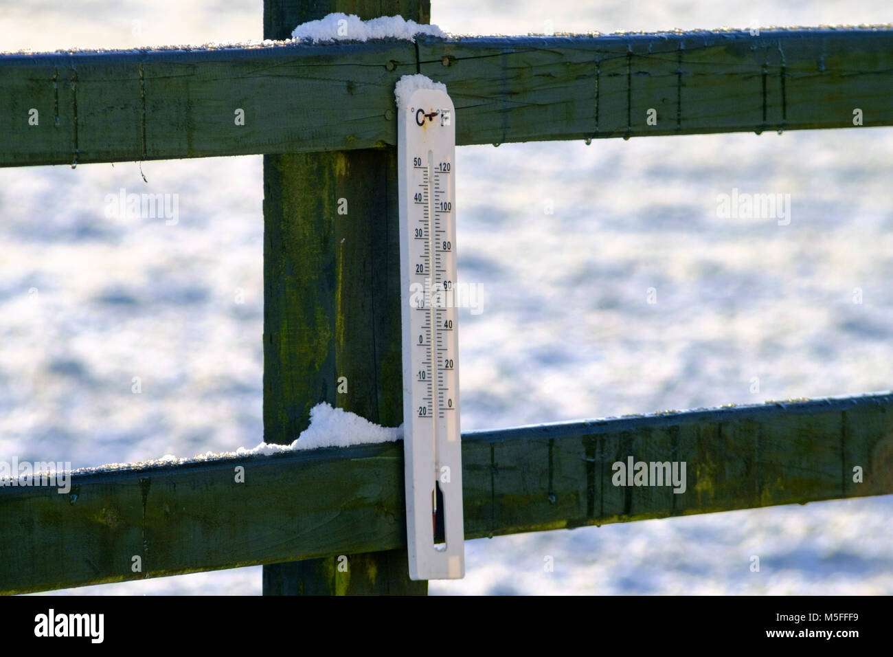 Thermometer montiert Holzzaun mit Schnee bestäubt. Carmarthenshire. West Wales. UK. Stockfoto