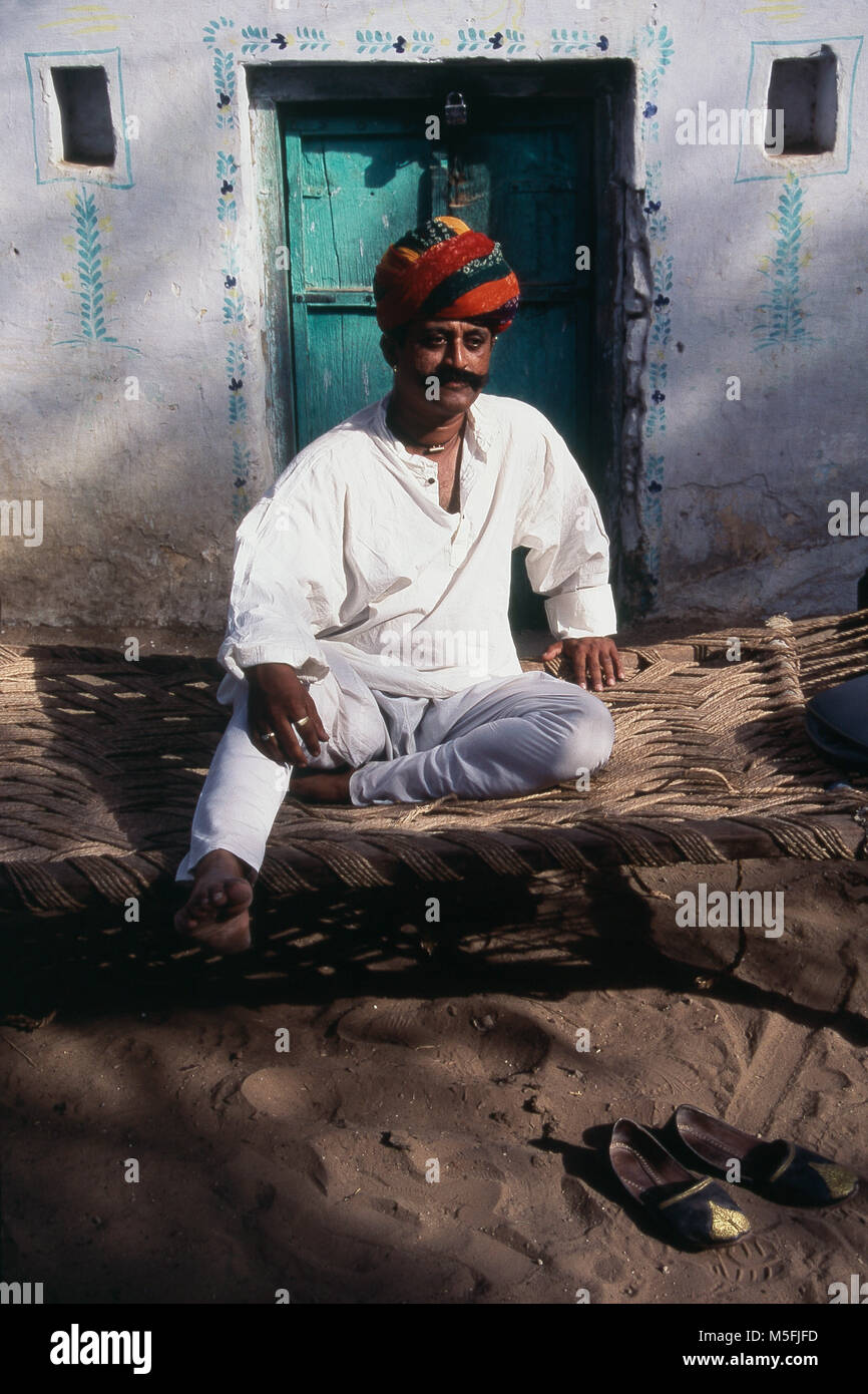 Rajasthani Mann ruhen außerhalb seines Hauses, Pushkar, Rajasthan, Indien Stockfoto