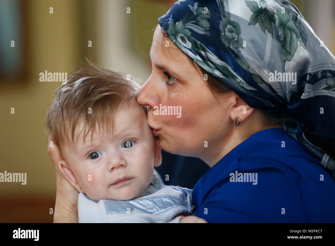Belarus, die Stadt Gomel, St. Nikolaus Kloster. 11. Juni 2016. Die Taufe des Kindes. eine Mutter küsst ein Baby. Mutter erbarmt sich ihr Sohn. Kind und Mutter Stockfoto
