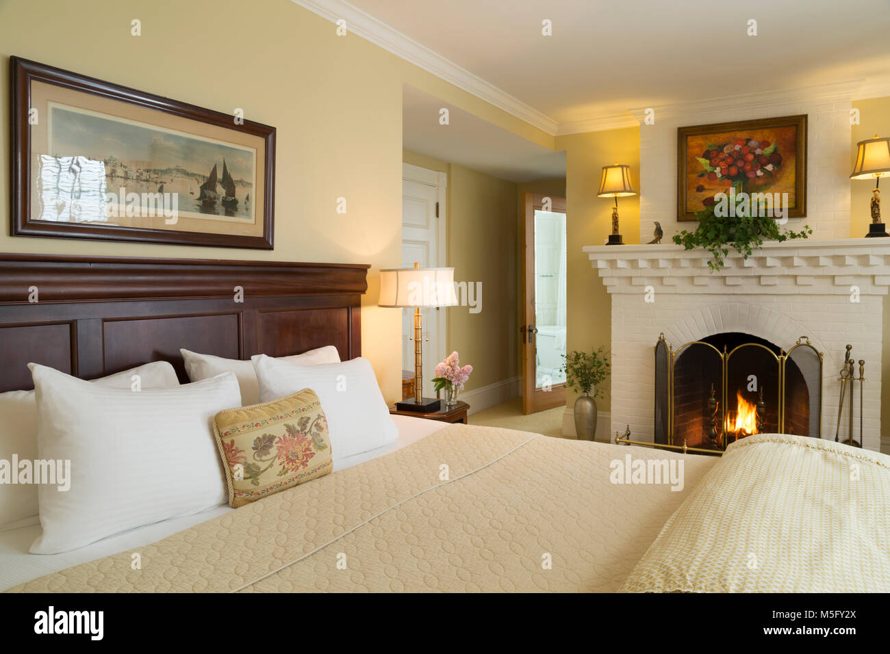Schlafzimmer mit Kamin und gelben Farbschema, Blair Hill Inn, Greenville, Maine Stockfoto