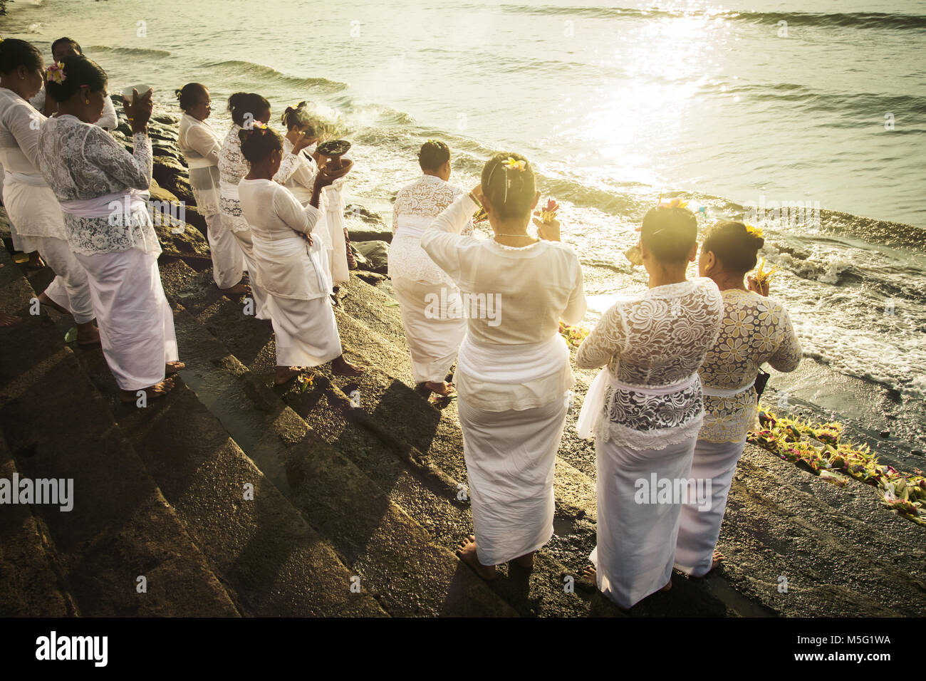 Gruppe der balinesischen hinduistischen Frauen Gott anbeten auf Padang Galak Strand an der Melasti Zeremonie. Einzigartig hohen Winkel über die Schulter schauen in Sun anzeigen Stockfoto