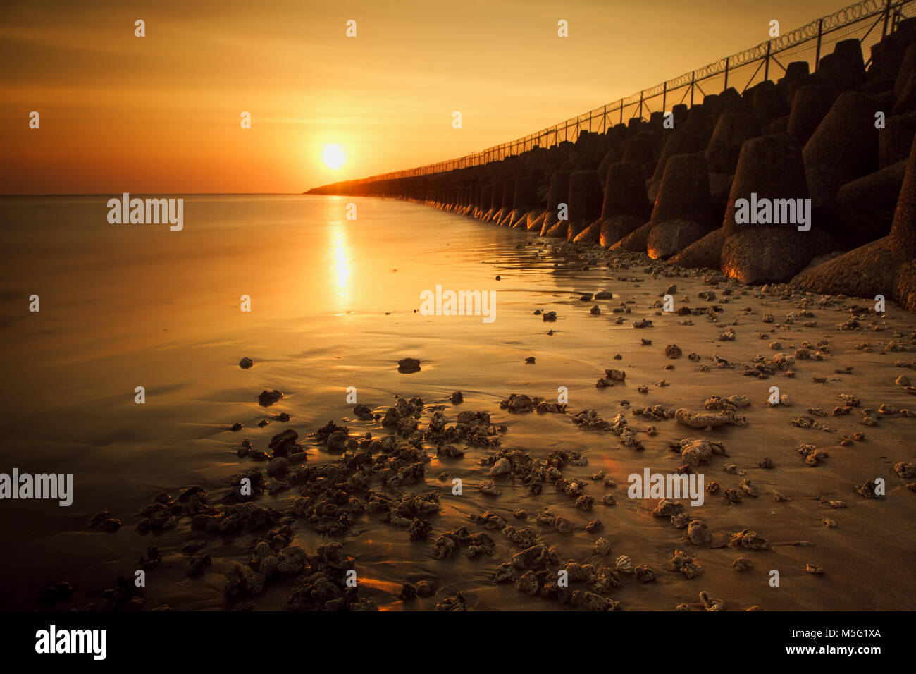 Atemberaubenden Sonnenuntergang Blick von Neben Bali Flughafen Landebahn mit Tetrapods am Strand. Das ist, was man für eine Aussicht auf den Sonnenuntergang im schönen Bali erwarten können Stockfoto