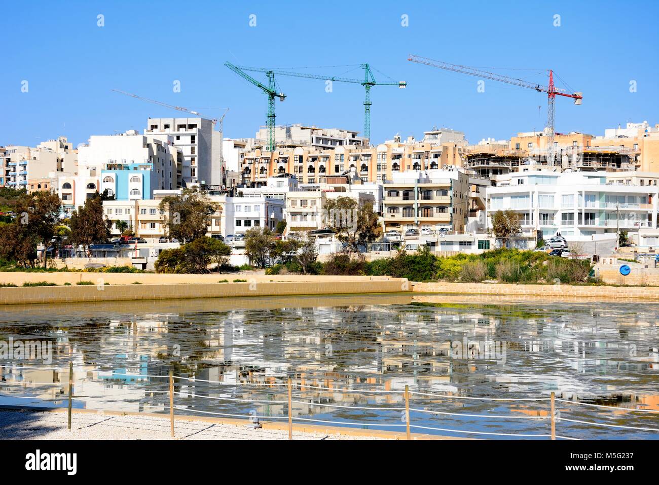 Blick auf die Salinen mit Gebäuden und Bau-Krane nach hinten in Salina Bay, Bugibba, Malta, Europa. Stockfoto