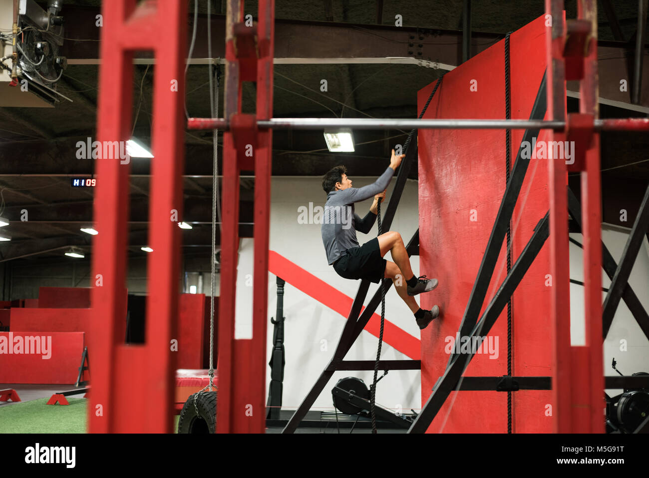 Muskulöse mann Klettern eine Wand mit Seil Stockfoto