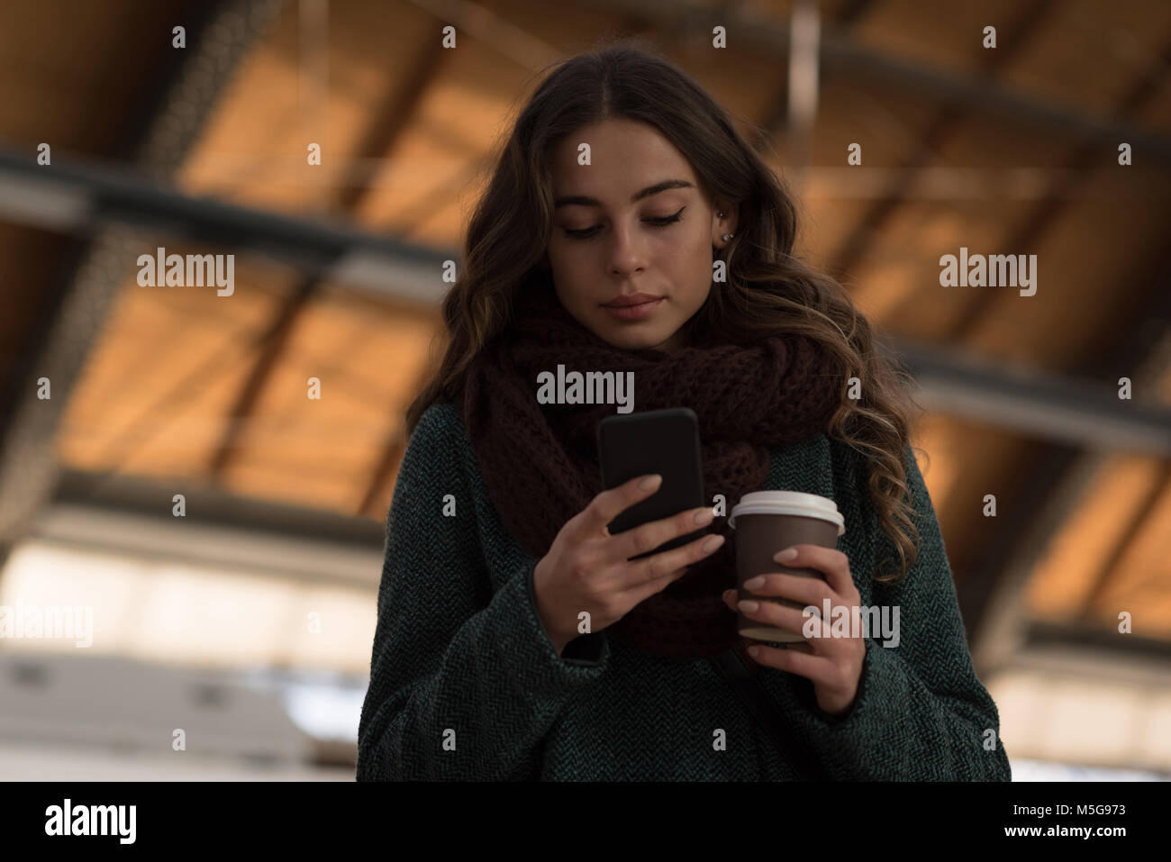 Eine Frau mit Handy am Bahnhof Stockfoto