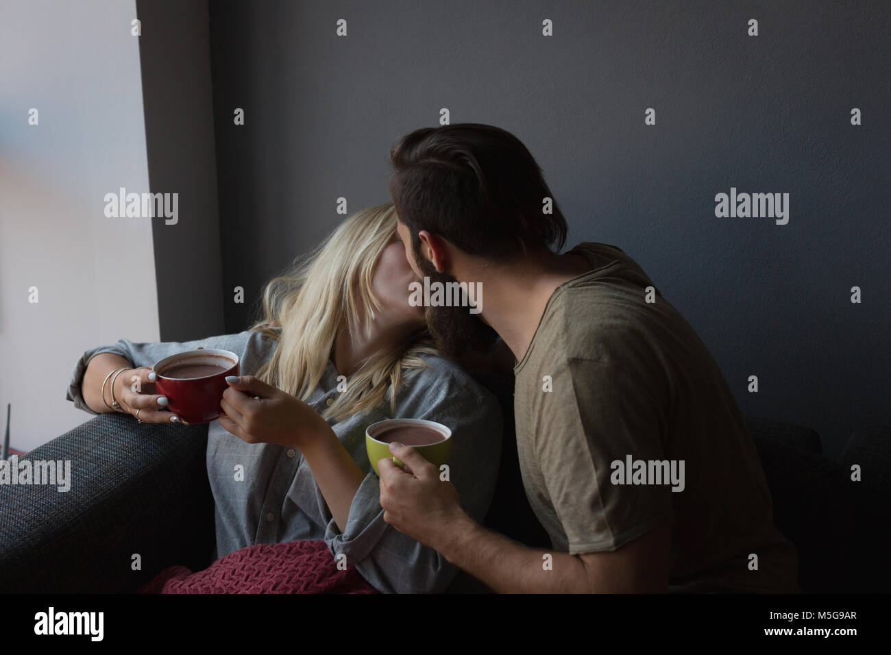 Paar einander küssen während Kaffee im Wohnzimmer Stockfoto
