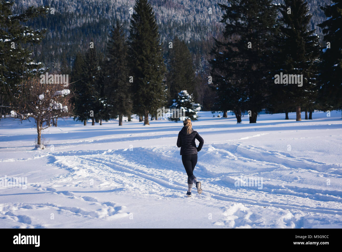 Athletische Frau joggen auf verschneite Landschaft Stockfoto
