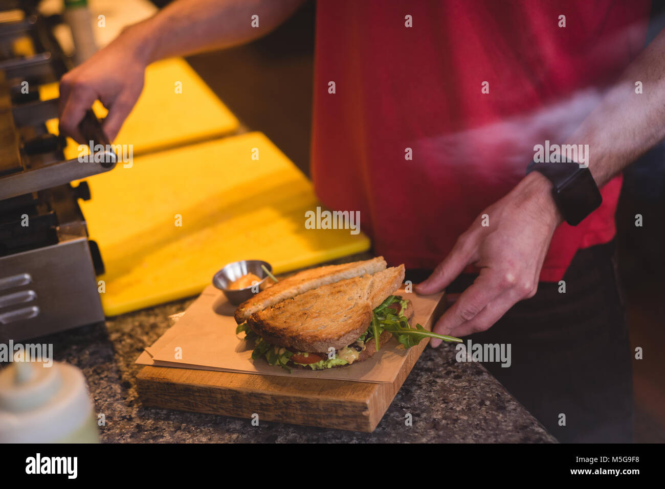 Männliche kellner Vorbereitung sandwich im Cafe Stockfoto