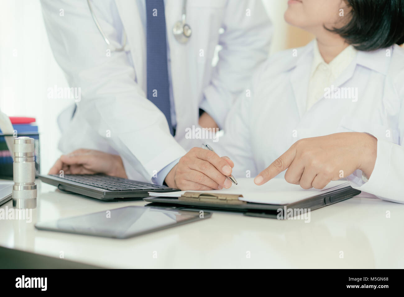 Zwei Doktoren der Analyse und Beratung über medizinische Aufzeichnung im modernen Krankenhaus. Asiatische Ärzte reden über Bericht. Stockfoto