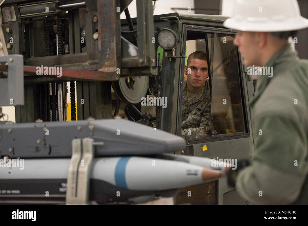 Älterer Flieger Kevin Clemons, zum 3 Munition Geschwader zugewiesen, betreibt ein Gabelstapler während Airman 1st Class Jonathan Catalano als er Boden führt ein Rack mit inerten kleiner Durchmesser Bomben bei Bereitschaft Ausbildung bei Joint Base Elmendorf-Richardson, Alaska, Feb 9, 2018. Der kleine Durchmesser Bombe ist eine präzise und genaue Waffe, mit der F-22 Raptor entscheidende Air Power zu liefern. (U.S. Air Force Stockfoto