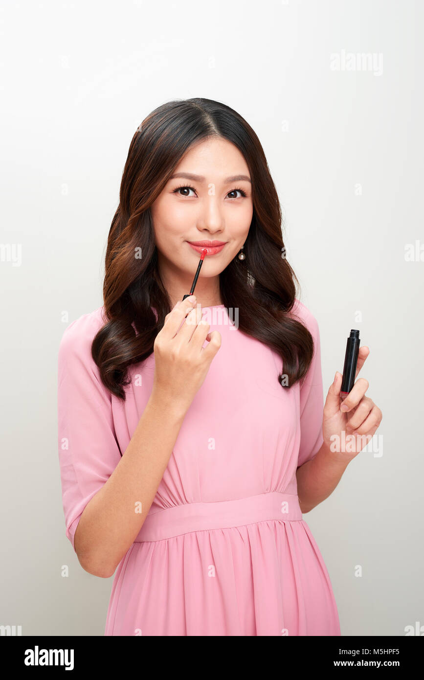 Schöne asiatische Frau mit rotem Lipgloss und es anwenden, Stockfoto