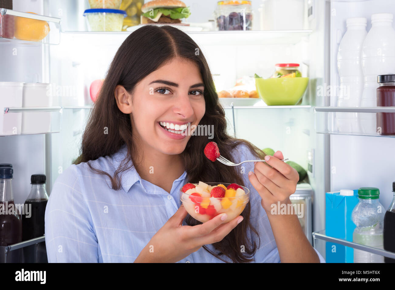 Nahaufnahme einer jungen Frau das Essen von frischem Obst in der Schüssel Stockfoto