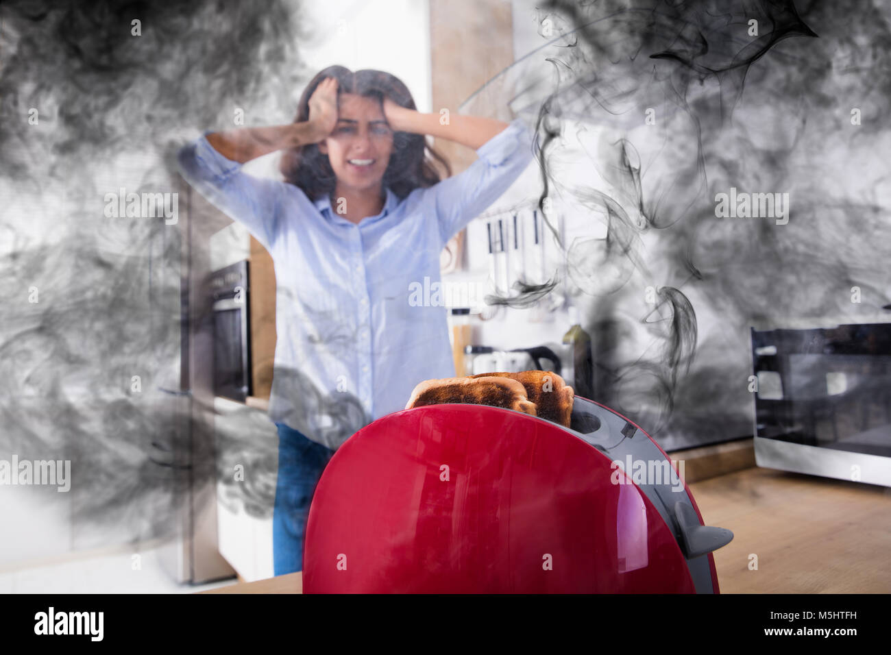 Frustrierte junge Frau bei Burnt Toast aus der Toaster in der Küche Stockfoto