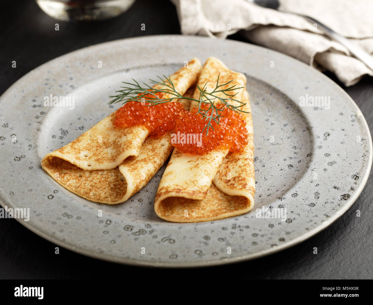 Russische Blinis mit rotem Kaviar und Dill auf einem grauen Platte closeup Stockfoto