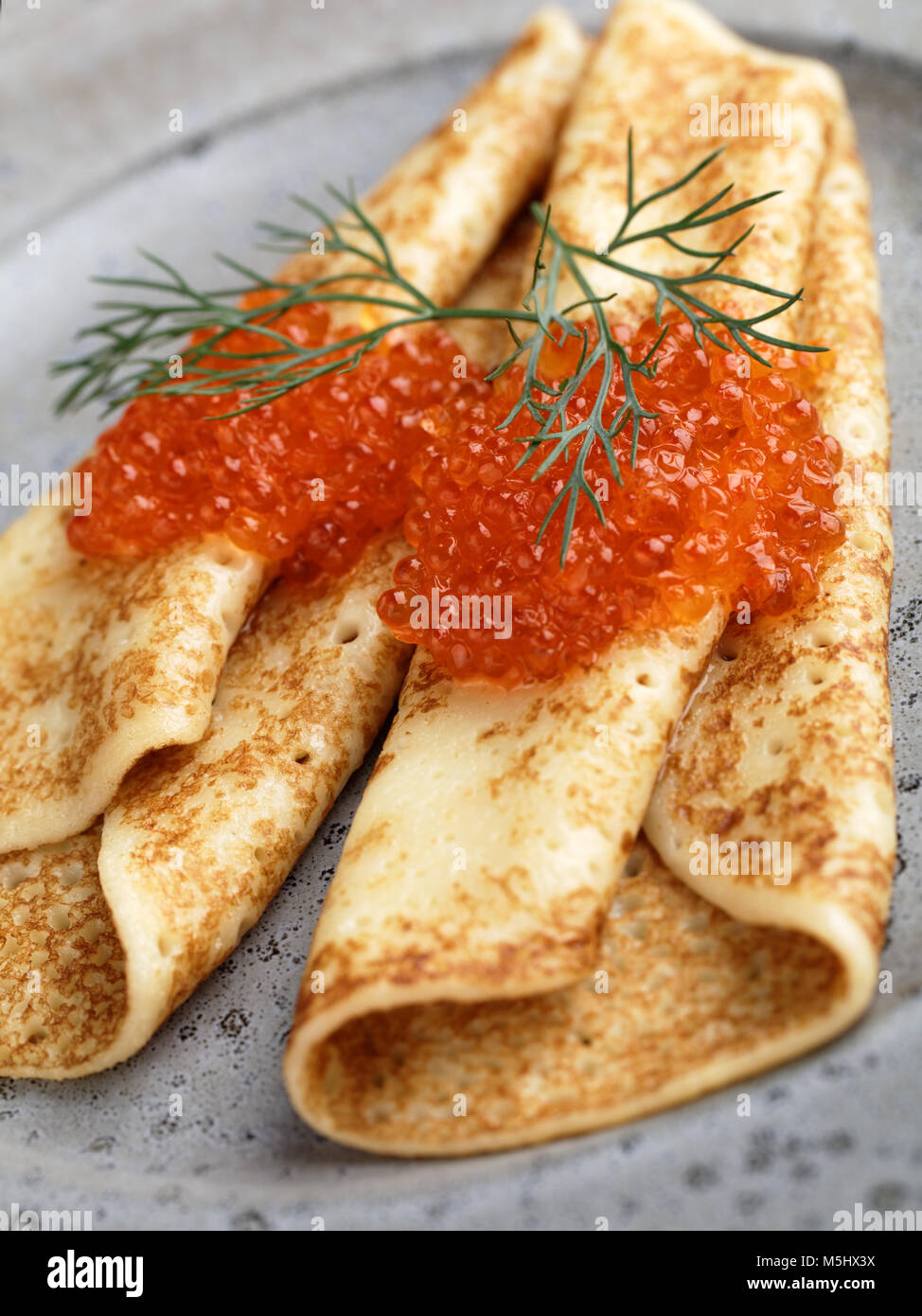 Russische Blinis mit rotem Kaviar und Dill auf einem grauen Platte closeup Stockfoto