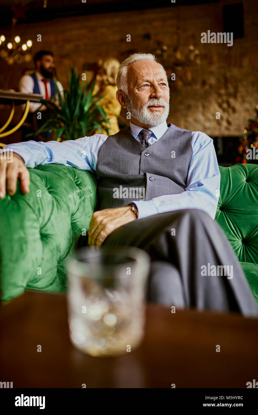 Portrait von eleganten älterer Mann sitzt auf der Couch in einer Bar Stockfoto