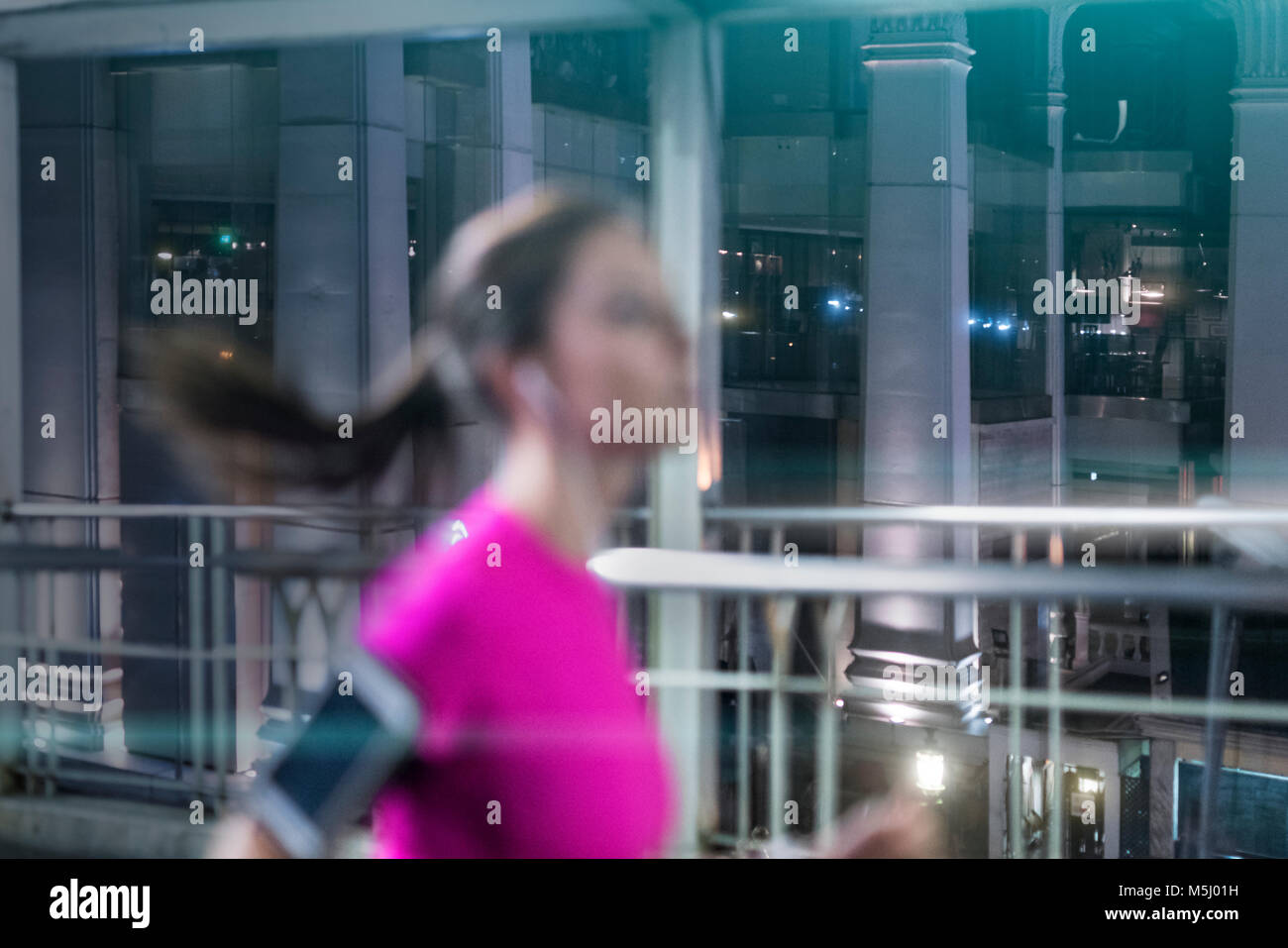 Junge Frau in rosa Sportshirt läuft in der Stadt bei Nacht Stockfoto