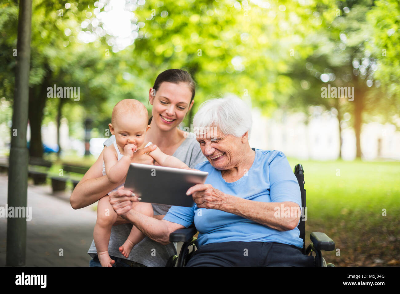 Großmutter, Tochter und Enkelin Spaß mit Tablet-PC in einem Park Stockfoto